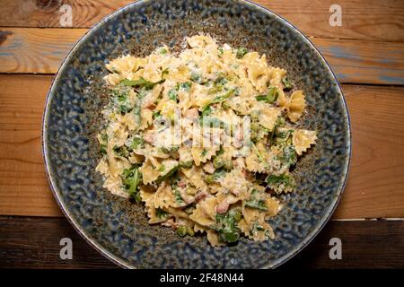 Une délicieuse assiette de parmesan Pancetta et de pâtes Pea une table de cuisine en bois Banque D'Images