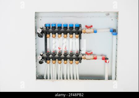 Nouveau collecteur de système de chauffage au sol, tuyaux et vannes en plastique visibles, desservant six circuits Banque D'Images
