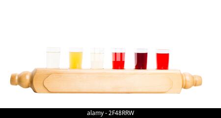 Mélange de teintures alcoolisées. Six verres avec différentes teintures de fruits servis dans un style national sur un panneau rustique en bois. Isolé sur un fond blanc. Banque D'Images