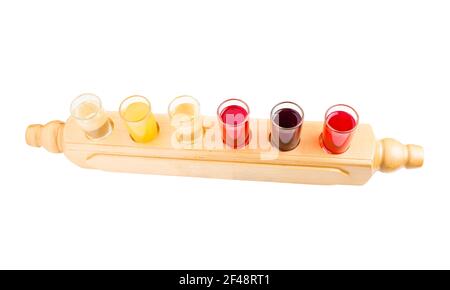 Mélange de teintures alcoolisées. Six verres avec différentes teintures de fruits servis dans un style national sur un panneau rustique en bois. Isolé sur un fond blanc. Banque D'Images