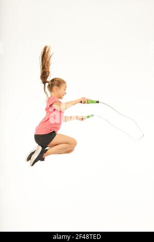 Adorable fille sportive tenant une corde à sauter et sautant Banque D'Images
