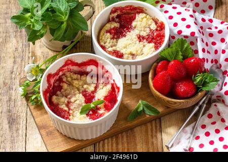 Dessert été cuisine maison. Les fraises s'émietlent dans un plat de cuisson et les fraises fraîches sur une table rustique en bois. Banque D'Images
