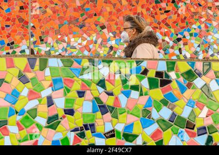 Düsseldorf, NRW, Allemagne, 19 mars 2021. Une femme en FFP2/KN95 masque de visage marche le long du mur de mosaïque 'Rivertime' par Hermann-Josef Kuhna sur les rives du Rhin à Dusseldorf, capitale de NRW. Les mesures de confinement devraient augmenter une fois de plus en Allemagne, le taux d'incidence sur 7 jours atteignant un seuil crucial de 100 000 habitants. Alors que Düsseldorf s'élève aujourd'hui relativement bien à 63, les chiffres de l'Allemagne ont augmenté à 95.6 Banque D'Images