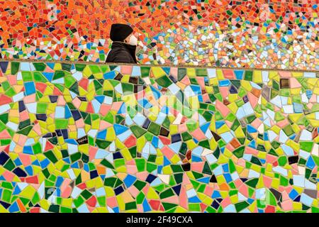 Düsseldorf, NRW, Allemagne, 19 mars 2021. Une femme en FFP2/KN95 masque de visage marche le long du mur de mosaïque 'Rivertime' par Hermann-Josef Kuhna, sur les rives du Rhin à Dusseldorf, capitale de NRW. Les mesures de confinement devraient augmenter une fois de plus en Allemagne, le taux d'incidence sur 7 jours atteignant un seuil crucial de 100 000 habitants. Alors que Düsseldorf s'élève aujourd'hui relativement bien à 63, les chiffres de l'Allemagne ont augmenté à 95.6 Banque D'Images