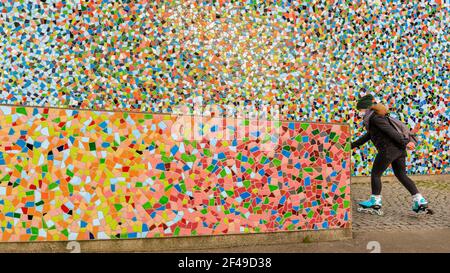 Düsseldorf, NRW, Allemagne, 19 mars 2021. Une femme en FFP2/KN95 masque le visage skate devant le mur de mosaïque 'Rivertime' par Hermann-Josef Kuhna sur les rives du Rhin à Dusseldorf, capitale de NRW. Les mesures de confinement devraient augmenter une fois de plus en Allemagne, le taux d'incidence sur 7 jours atteignant un seuil crucial de 100 000 habitants. Alors que Düsseldorf s'élève aujourd'hui relativement bien à 63, les chiffres de l'Allemagne ont augmenté à 95.6 Banque D'Images