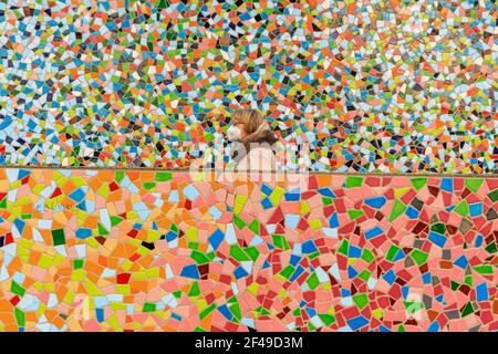 Düsseldorf, NRW, Allemagne, 19 mars 2021. Une femme en FFP2/KN95 masque de visage marche le long du mur de mosaïque 'Rivertime' par Hermann-Josef Kuhna sur les rives du Rhin à Dusseldorf, capitale de NRW. Les mesures de confinement devraient augmenter une fois de plus en Allemagne, le taux d'incidence sur 7 jours atteignant un seuil crucial de 100 000 habitants. Alors que Düsseldorf s'élève aujourd'hui relativement bien à 63, les chiffres de l'Allemagne ont augmenté à 95.6 Banque D'Images