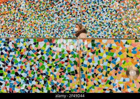 Düsseldorf, NRW, Allemagne, 19 mars 2021. Une femme en FFP2/KN95 masque de visage marche le long du mur de mosaïque 'Rivertime' par Hermann-Josef Kuhna sur les rives du Rhin à Dusseldorf, capitale de NRW. Les mesures de confinement devraient augmenter une fois de plus en Allemagne, le taux d'incidence sur 7 jours atteignant un seuil crucial de 100 000 habitants. Alors que Düsseldorf s'élève aujourd'hui relativement bien à 63, les chiffres de l'Allemagne ont augmenté à 95.6 Banque D'Images