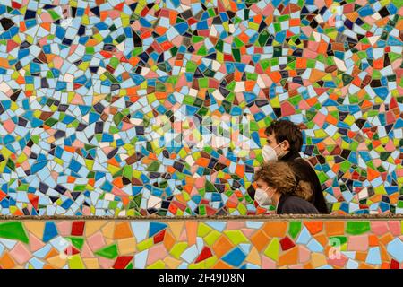 Düsseldorf, NRW, Allemagne, 19 mars 2021. Deux personnes en FFP2/KN95 masques de visage marchent devant le mur de mosaïque 'Rivertime' par Hermann-Josef Kuhna sur les rives du Rhin à Dusseldorf, capitale de NRW. Les mesures de confinement devraient augmenter une fois de plus en Allemagne, le taux d'incidence sur 7 jours atteignant un seuil crucial de 100 000 habitants. Alors que Düsseldorf s'élève aujourd'hui relativement bien à 63, les chiffres de l'Allemagne ont augmenté à 95.6 Banque D'Images