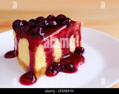 Tranche de cheesecake au four nappée d'une sauce aux myrtilles appétissante table en bois Banque D'Images