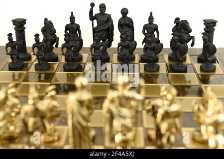 Noir contre pièces d'échecs de soldat de l'armée d'or sur un échiquier sur fond blanc Banque D'Images