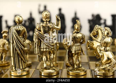 Arrière de la reine d'or, le roi centurion et la pièce d'échecs de chevalier figurines sur échiquier face à l'armée noire opposée Banque D'Images