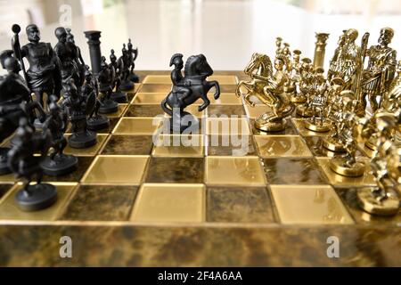 Figurines d'échecs noir et or en métal chevalier sur l'attaque à cheval à l'échiquier avec des armées opposées Banque D'Images