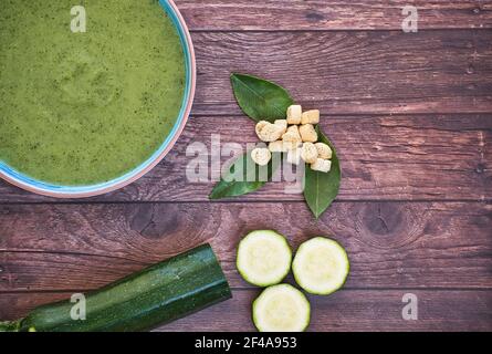 Soupe de detox de légumes frais à base de pois dans une assiette sur une table en bois brun avec concombres et poivre vert, vue de dessus avec espace pour le texte. Savoureux Banque D'Images