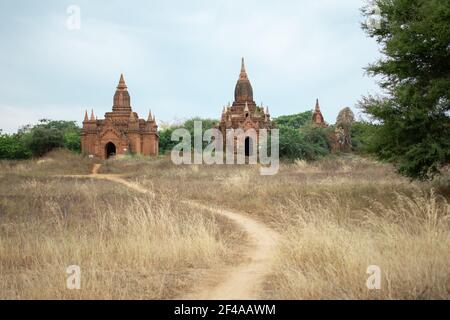 BAGAN, NYAUNG-U, MYANMAR - 2 JANVIER 2020 : un chemin de terre menant vers les temples bouddhistes historiques au loin Banque D'Images