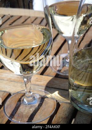 Un cliché vertical d'une tasse en verre et d'une bouteille remplie avec vin blanc placé sur une table en bois Banque D'Images