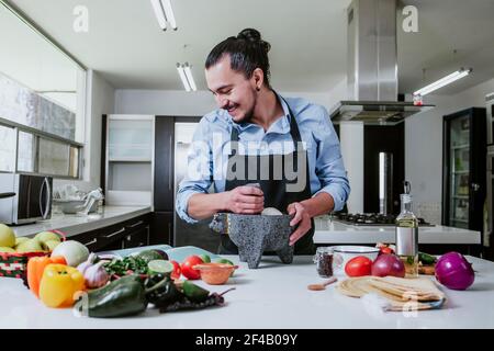latino-homme cuisant à la maison de la salade ou de la sauce mexicaine Dans la cuisine à la maison dans la ville de Mexico Banque D'Images