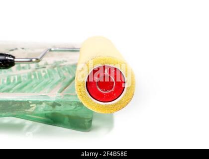 Gros plan du rouleau de peinture et du bac nettoyés. Vue latérale partielle du grand rouleau en mousse épaisse jaune en plastique vert pour le nettoyage du rouleau et du tr Banque D'Images