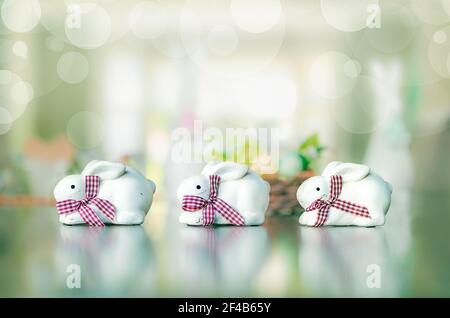 Lapin sur table. Trois petites argiles blanches avec arceaux. Décoration de table ou toile de fond sur le thème de Pâques. Pointe ensoleillée brillante et abstraite défocused Banque D'Images