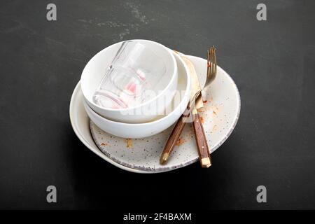 Pile d'assiettes vides et sales avec restes de nourriture sur fond sombre. Banque D'Images