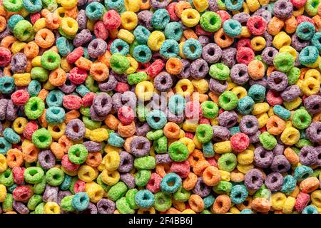 Céréales multicolores, plein cadre, plat. Vue de dessus des céréales colorées pour le petit déjeuner. Arrière-plan des céréales multigrains. Repas du matin pour les enfants. Banque D'Images