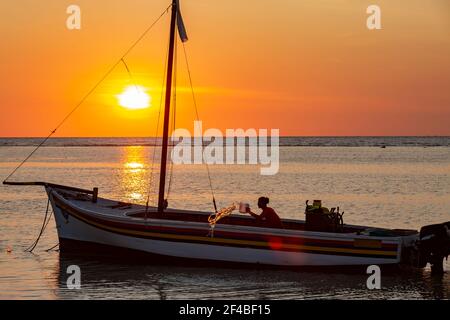 Pêcheur sur son bateau au coucher du soleil sur la plage de Flic en Flac, Maurice Banque D'Images