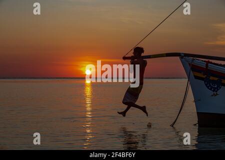 Pêcheur sur son bateau au coucher du soleil sur la plage de Flic en Flac, Maurice Banque D'Images