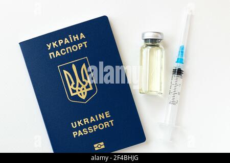 Gros plan d'une bouteille de vaccin contre le coronavirus et d'une seringue avec passeport bleu d'Ukraine sur fond blanc. Banque D'Images