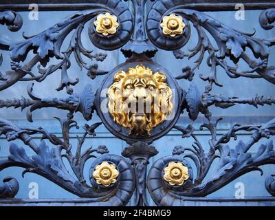 Vue rapprochée de la rambarde en fer forgé du balcon d'un bâtiment parisien décoré d'une tête de lion dorée Banque D'Images