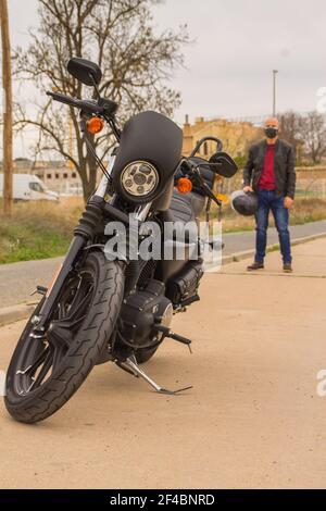 Un motard espagnol frais dans un masque de protection et un veste en cuir à proximité de sa moto avec un casque Banque D'Images