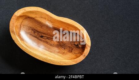 Petit bol en bois de rose poli sur table noire, vue rapprochée du dessus Banque D'Images