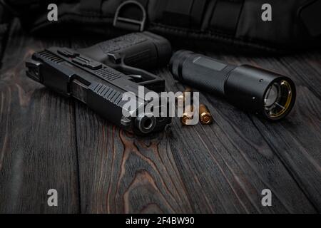 Un pistolet, des cartouches pour lui et un couteau pliant sur un fond sombre. Kit d'auto-défense et de survie. Armes à feu et armes à feu à bordure compacte. Banque D'Images