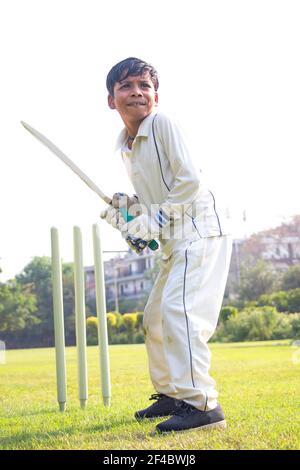 Un jeune garçon battait dans un équipement de protection pendant un cricket Banque D'Images