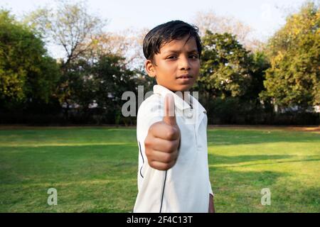 Un garçon dans l'uniforme de cricket et de pointage
