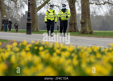 Hyde Park, Londres, Royaume-Uni. 20 mars 2021. Un certain nombre de manifestations anti-verrouillage sont prévues dans des villes du monde entier, y compris Londres. La police patrouille de nombreux endroits à des points de rendez-vous probables, y compris à Hyde Park, le premier jour du printemps au Royaume-Uni. Les jonquilles sont dans le parc alors que deux policiers marchent en portant des masques faciaux Banque D'Images