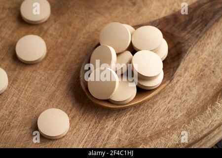 Comprimés de levure de bière sur une cuillère en bois - supplément nutritionnel Riche en vitamine B. Banque D'Images