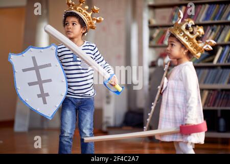 Un petit frère et une sœur habillés comme des chevaliers jouent dans une atmosphère gaie à la maison. Famille, maison, temps de jeu Banque D'Images