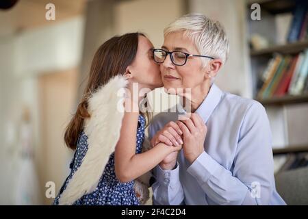 Bonne petite-fille embrassant grand-mère dans la joue à la maison Banque D'Images