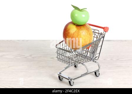 Pomme rouge et jaune et pomme verte en céramique à l'intérieur d'un chariot miniature sur une table en bois blanc au-dessus d'un arrière-plan blanc Banque D'Images