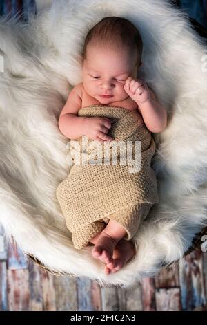 Adorable bébé de 2 semaines allongé dans un panier sur du blanc couverture souple Banque D'Images