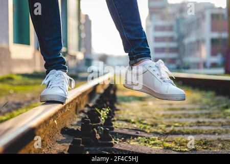 Femme en baskets blanches sur rail. Marche avec des chaussures de sport en ville Banque D'Images