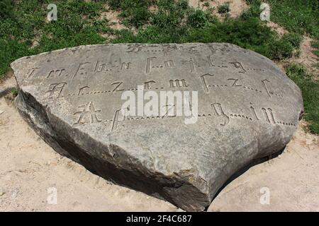 Ancienne inscription codée gravée par police gothique avec lettres manquantes sur un gros bloc, cette roche est mieux connue comme la pierre des Templiers selon Banque D'Images