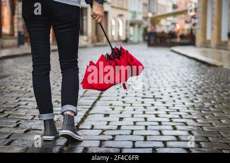 Femme tenant un parapluie rouge et elle marche dans la rue après la pluie. Vie urbaine Banque D'Images