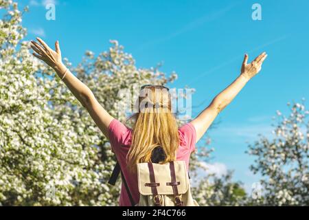 Bienvenue au printemps. Bonne femme caucasienne levant les bras ouverts et elle profite du printemps dans le verger en fleur. Femme se sentant libre Banque D'Images