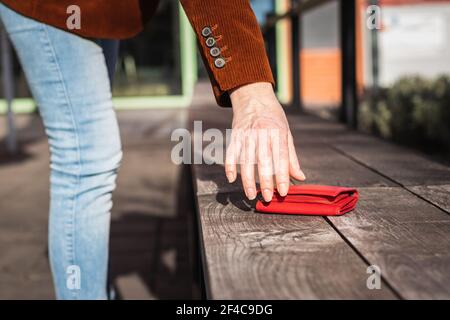 Femme prenant le portefeuille perdu du banc dans la ville. Une femme prend main portefeuille en cuir rouge dans la rue Banque D'Images