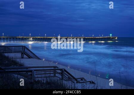 Des vagues floues autour de la jetée de Surf City la nuit Banque D'Images
