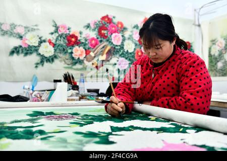 Juye, comté de Juye. 20 mars 2021. Le 20 mars 2021, un travailleur dessine une peinture réaliste sur le thème de la pivoine dans une coopérative de peinture professionnelle du canton de Qilin, dans le comté de Juye, dans la ville de Heze, dans la province de Shandong, dans l'est de la Chine. Heze est l'une des principales origines des fleurs de pivoine en Chine. La peinture sur le thème de la pivoine, de style réaliste, dans le cadre de la culture traditionnelle de Juye est devenue une technique unique pour les paysans locaux d'augmenter leurs revenus. Credit: Guo Xulei/Xinhua/Alamy Live News Banque D'Images