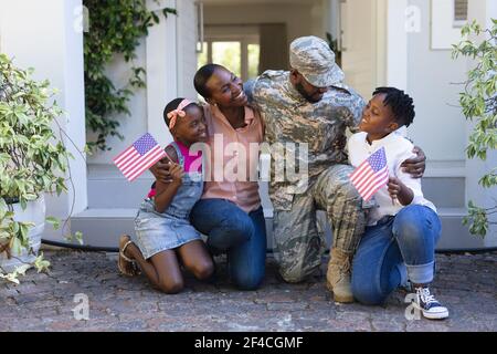 Un père militaire américain souriant embrasse sa femme et ses enfants avant de la maison Banque D'Images