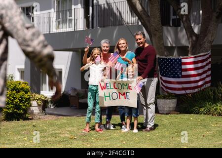 Un père de soldat caucasien et une réunion de famille à l'extérieur de la maison avec accueil et drapeaux américains Banque D'Images