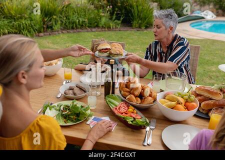 Souriante femme de race blanche au service de la famille avant de manger ensemble dans le jardin Banque D'Images