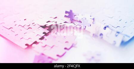 Les puzzles bleu-rose ne sont pas collectées sur une table blanche. Une tâche difficile. La destruction de l'ensemble. Banque D'Images